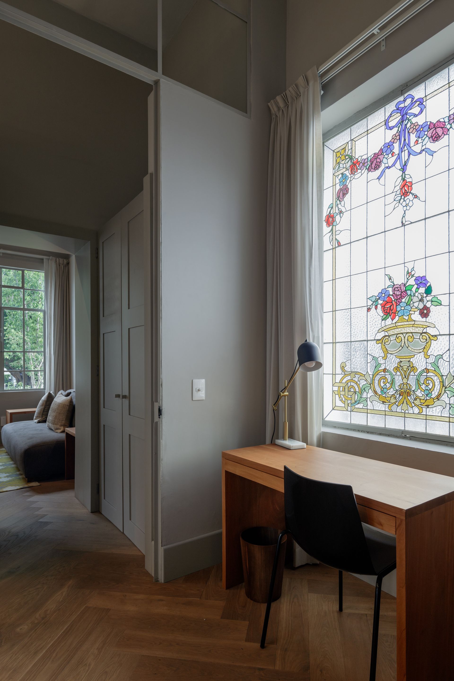 A room with a desk and chair in front of a stained glass window.