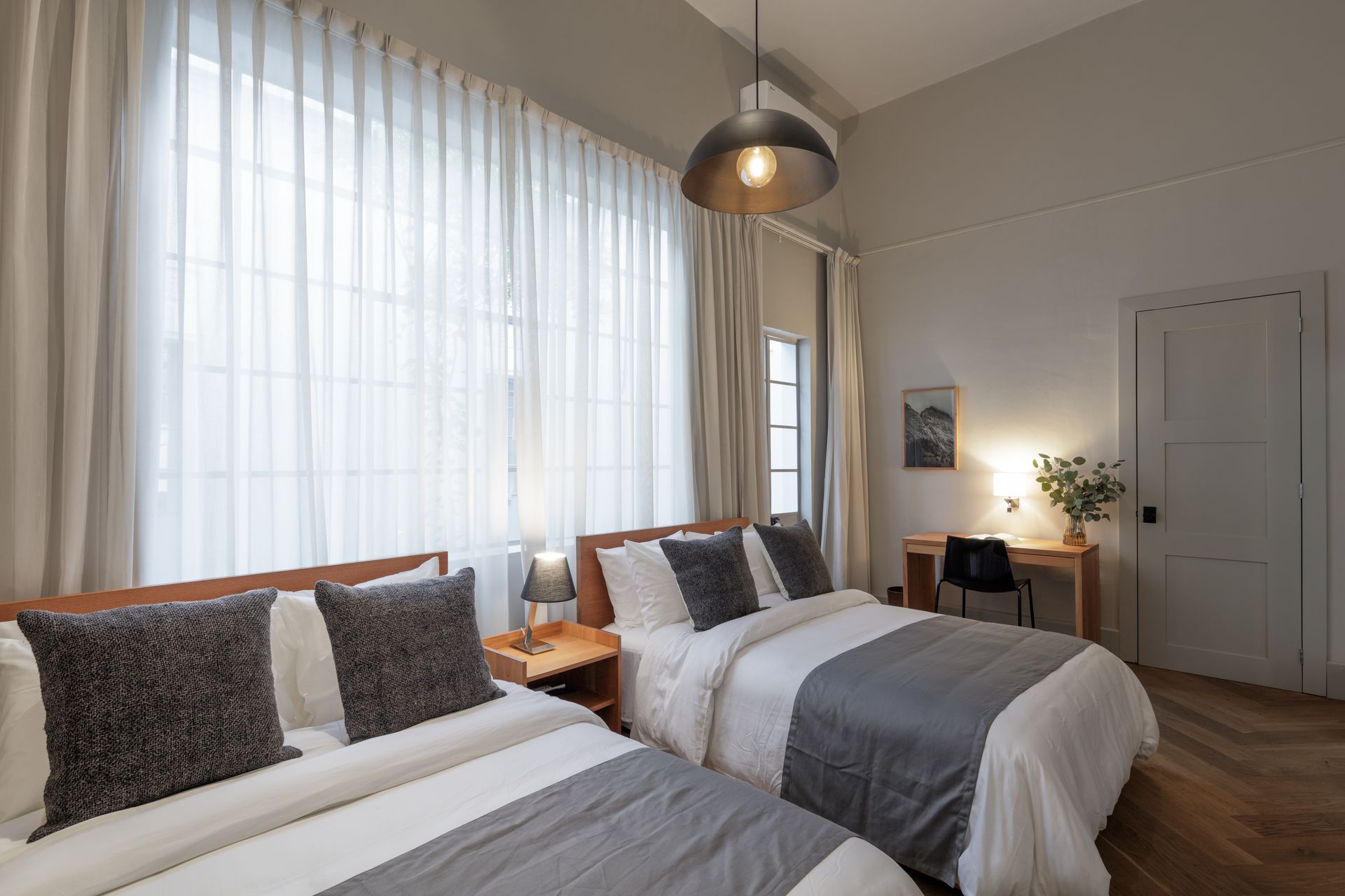 A hotel room with two beds and a desk.