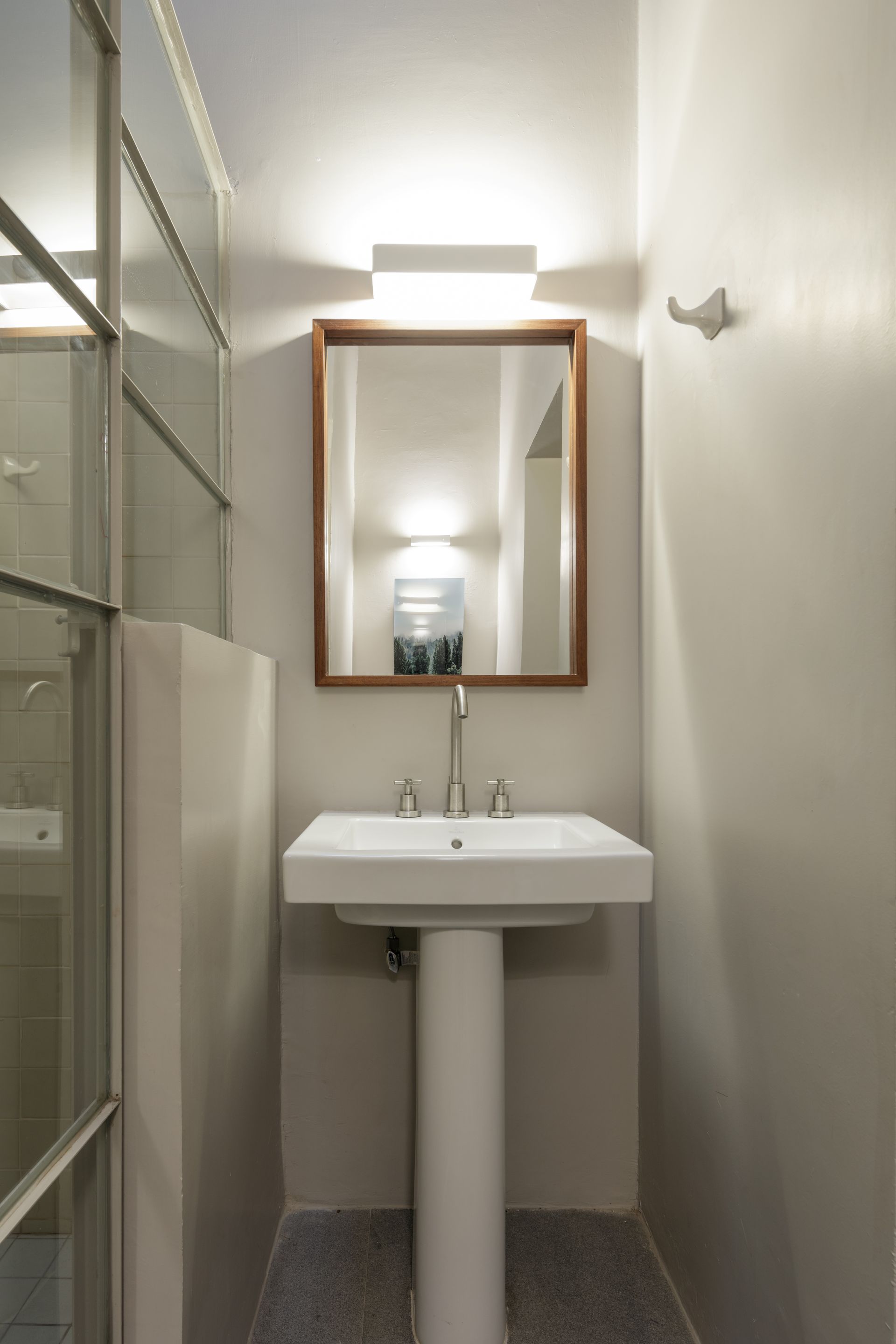 A bathroom with a pedestal sink and a mirror