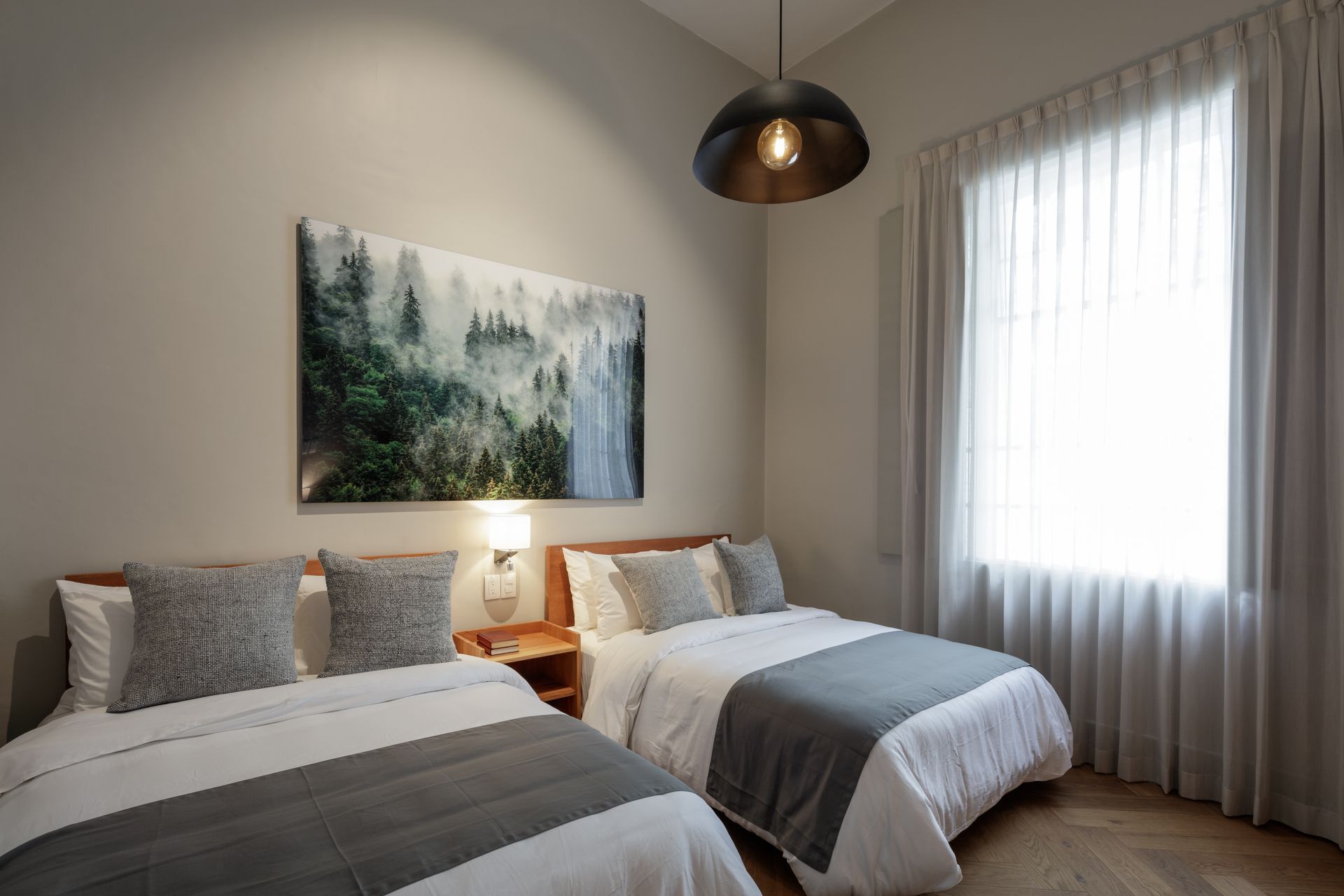 A bedroom with two beds and a painting on the wall.