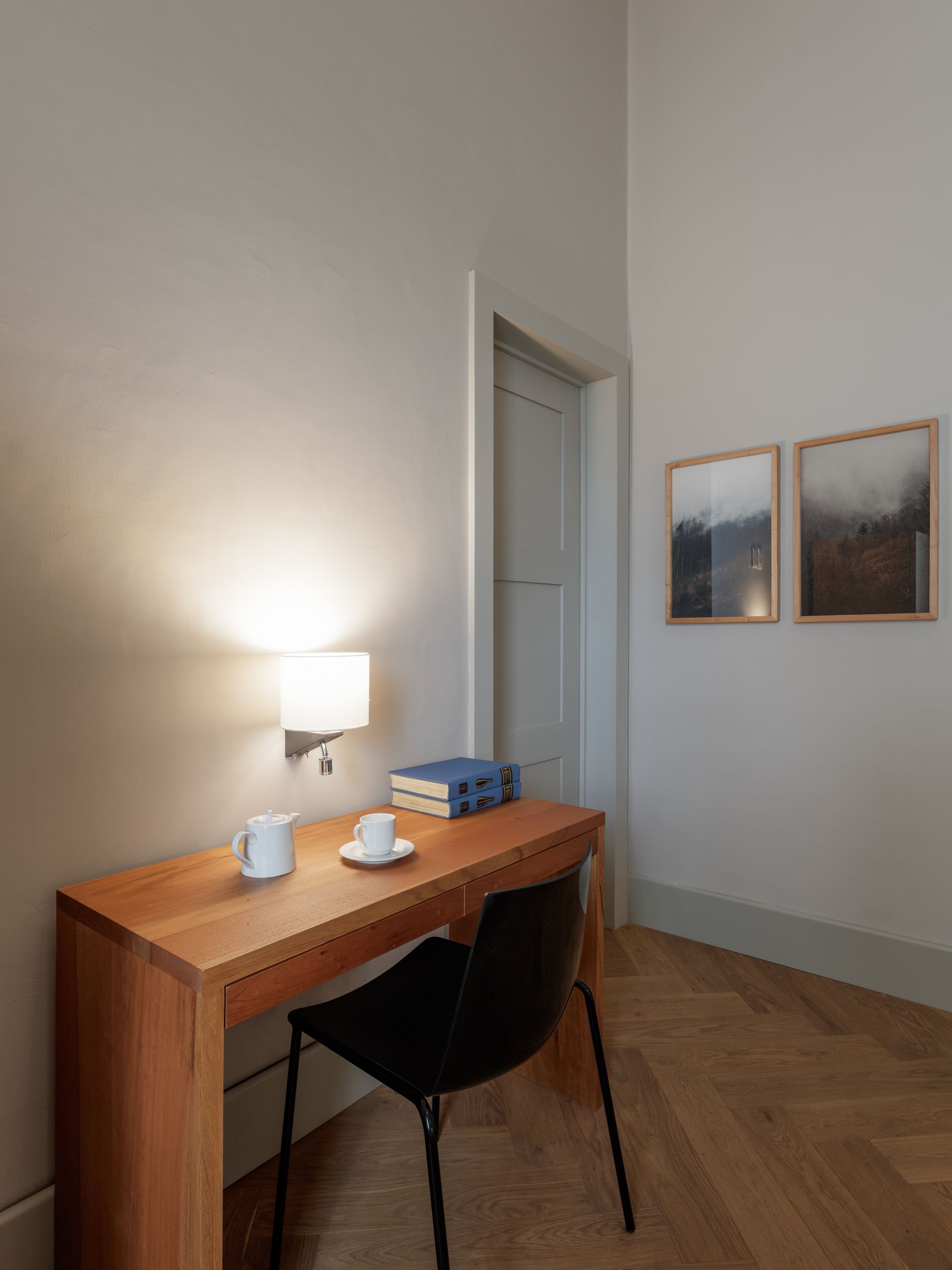 A wooden desk with a chair and a cup of coffee on it in a room.