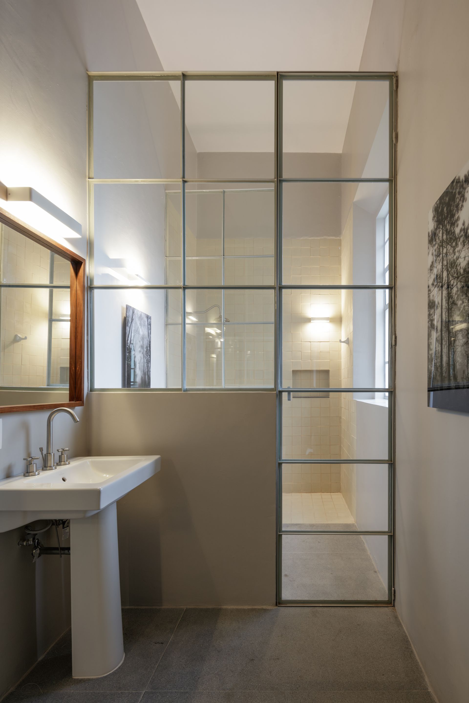 A bathroom with a sink , mirror and walk in shower.