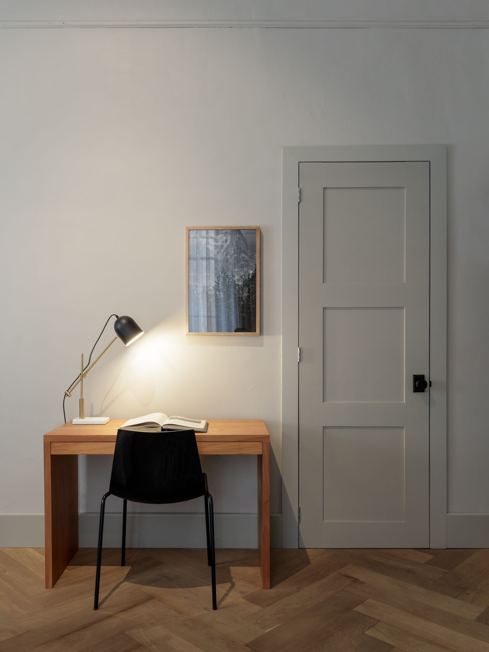A desk with a lamp and a chair in a room