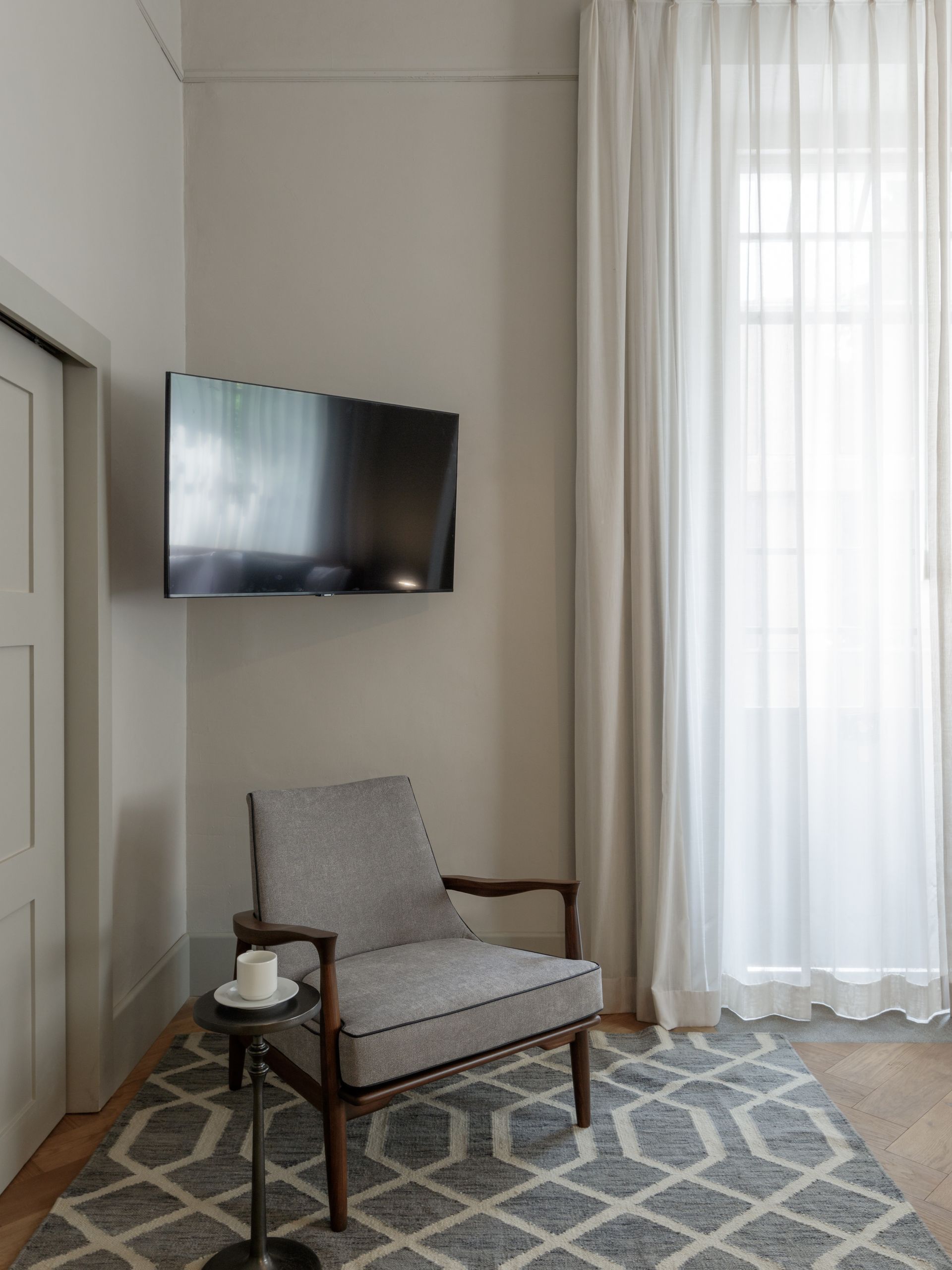 A living room with a chair and a television on the wall.
