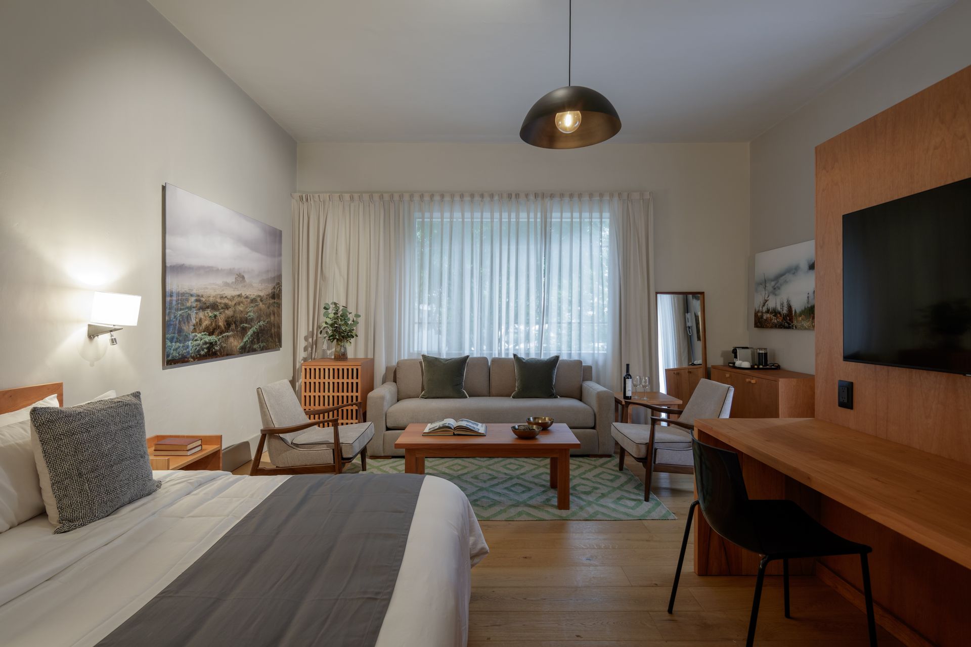 A hotel room with a bed , couch , table , chairs and television.