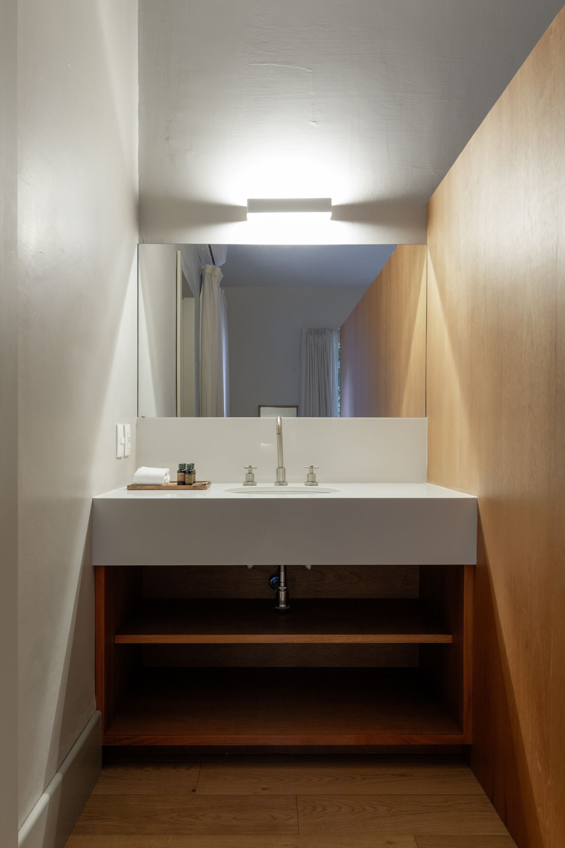 A bathroom with a sink , mirror and shelf.