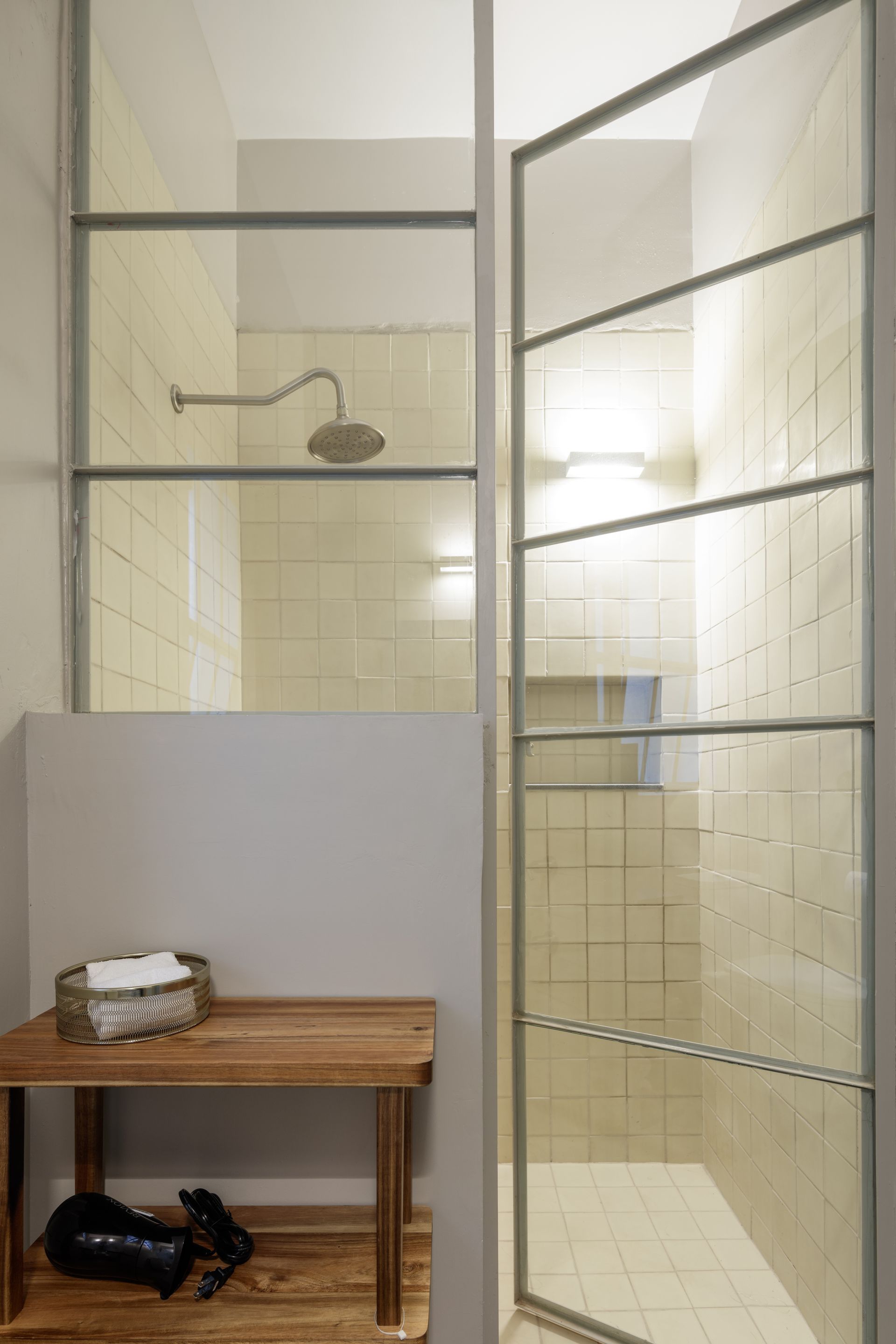 A bathroom with a walk in shower and a wooden bench.