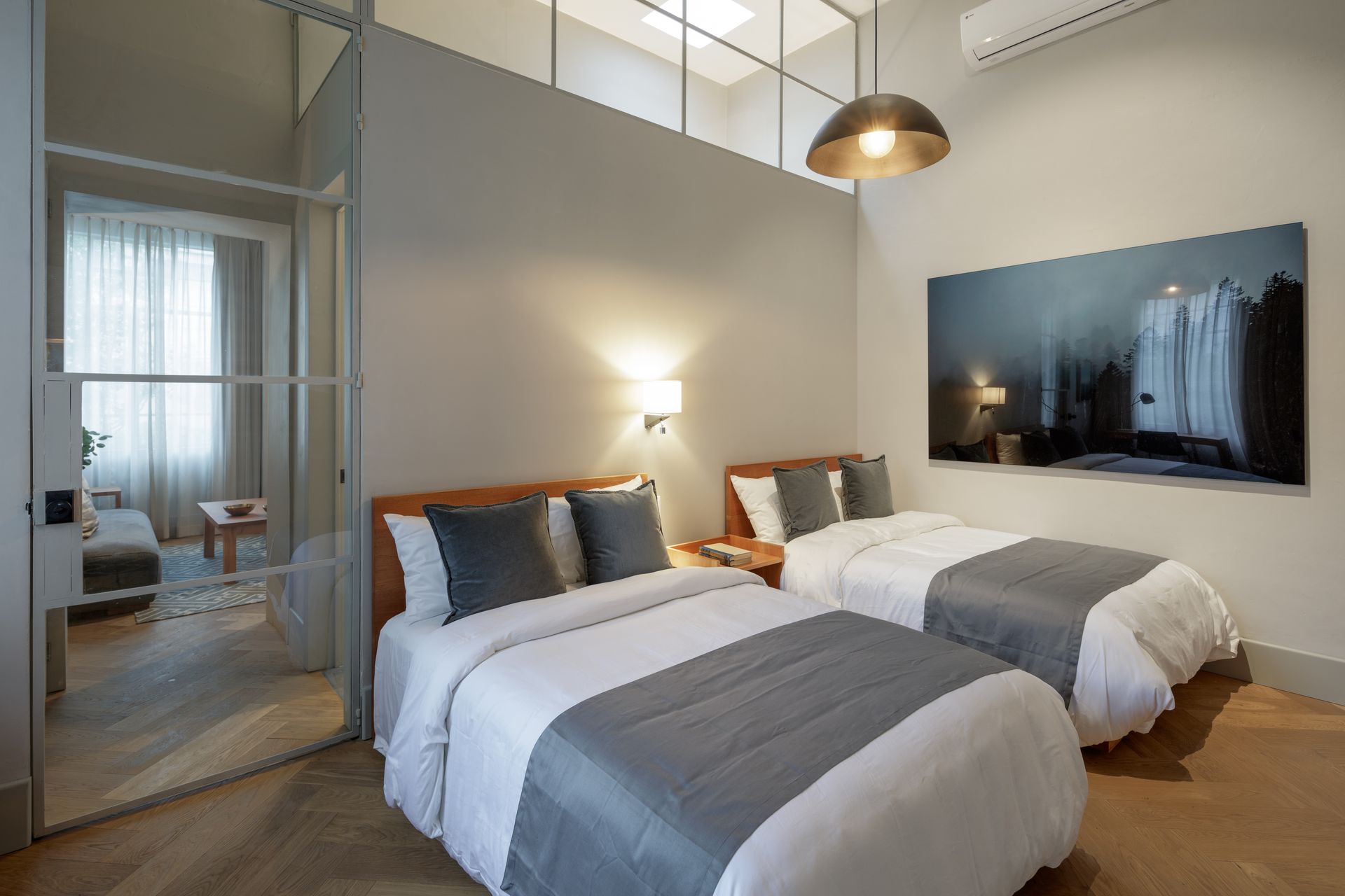 A bedroom with two beds and a painting on the wall.