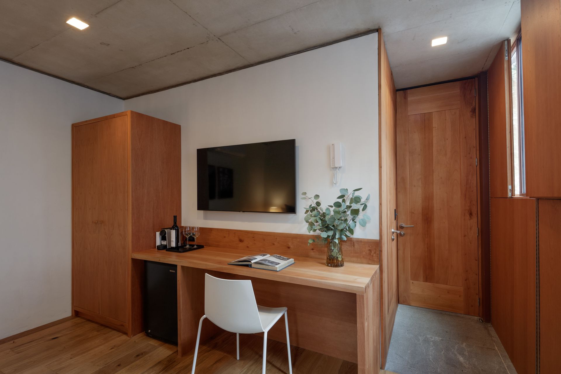 There is a desk with a chair and a television on the wall.