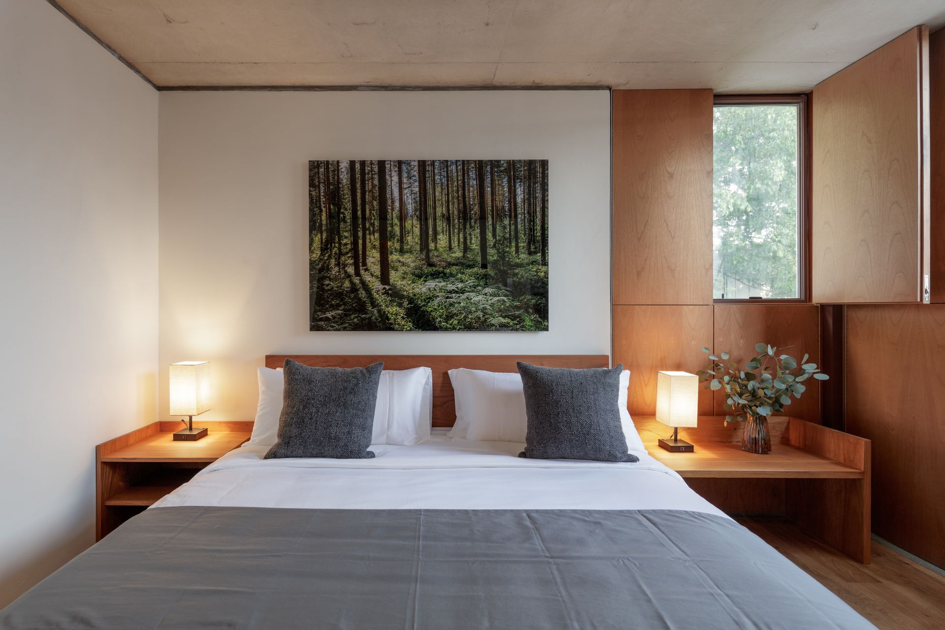 A bedroom with a bed and a painting on the wall above it.