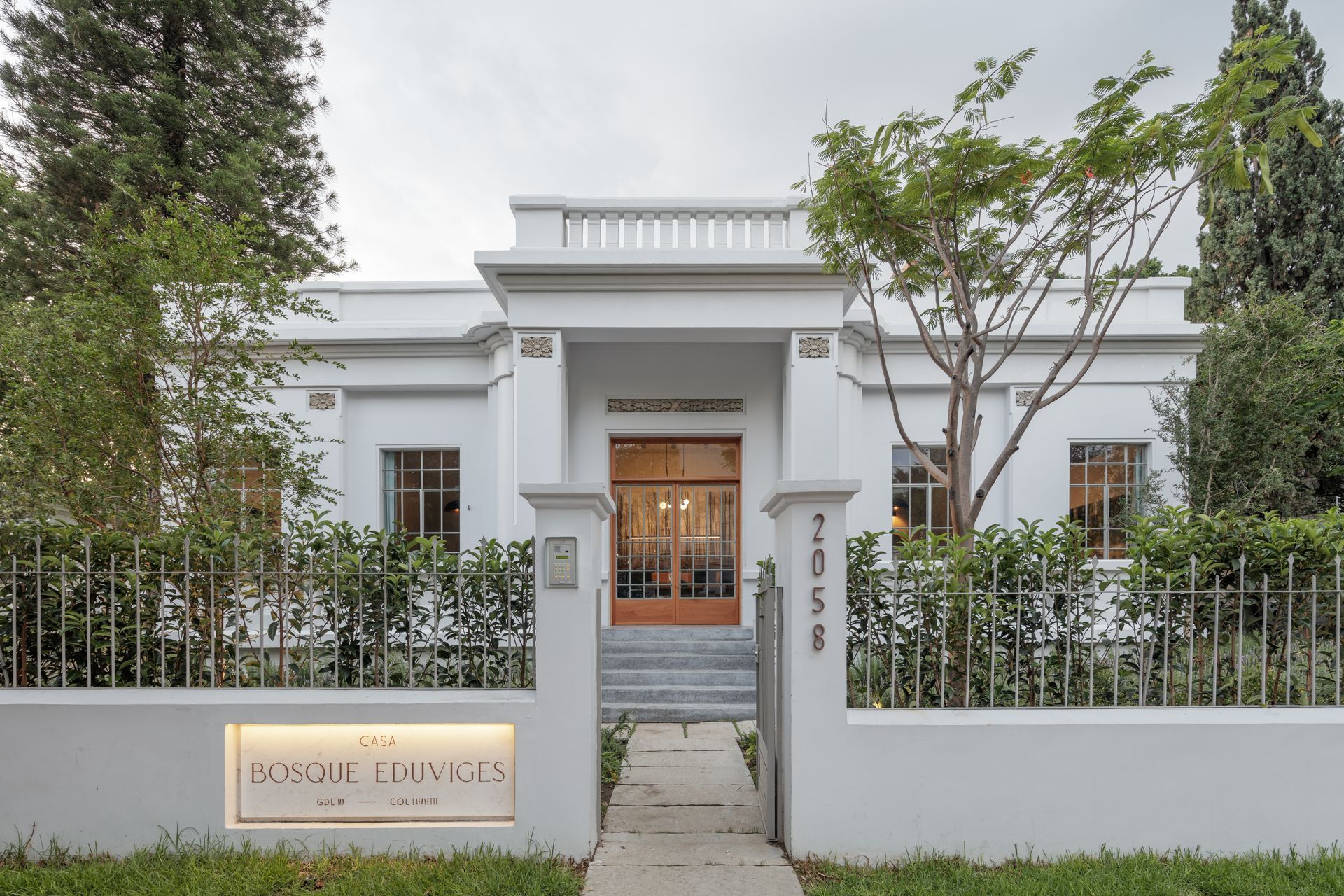 A white house with a fence and trees in front of it