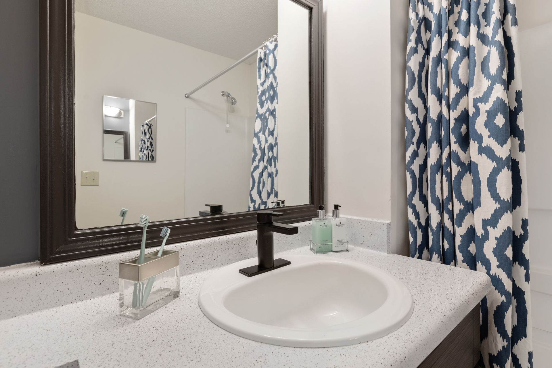 A bathroom with a sink , mirror and shower curtain.