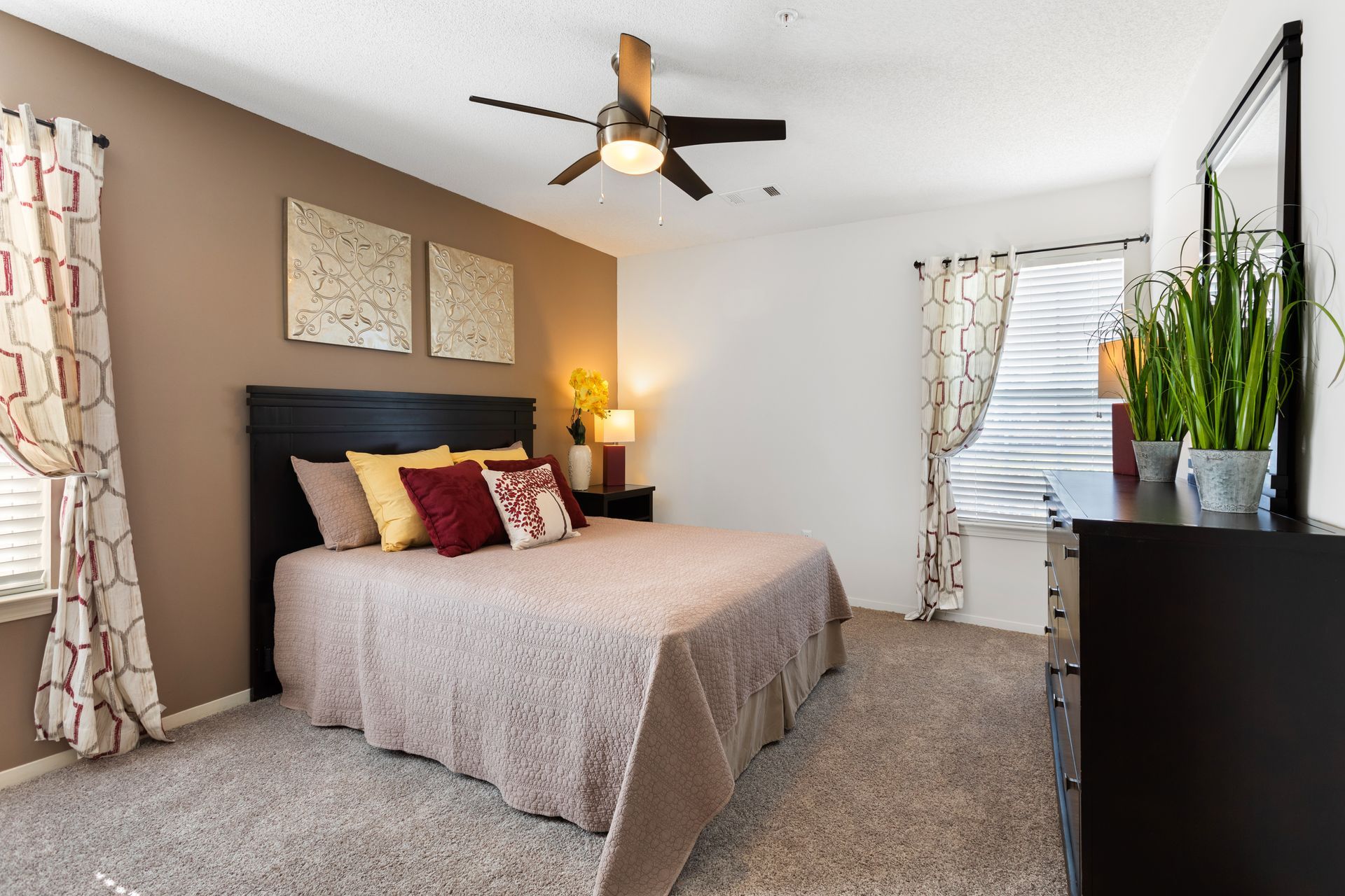 A bedroom with a bed , dresser , mirror and ceiling fan.