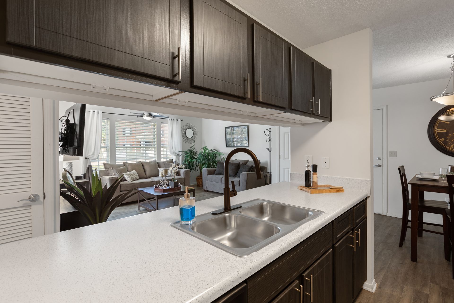 A kitchen with a sink and a view of a living room and dining room.