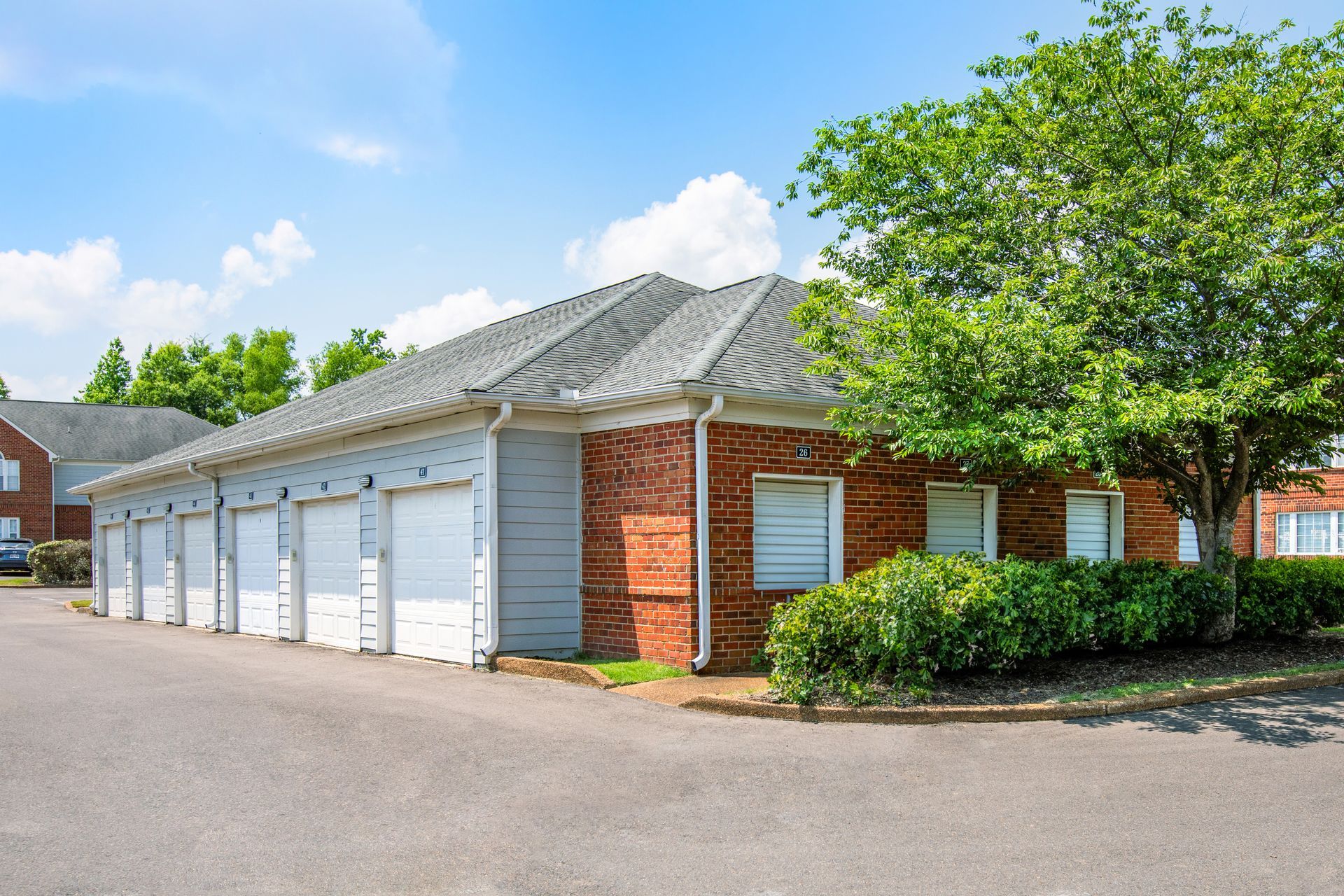 A brick building with white garage doors and a tree in front of it.