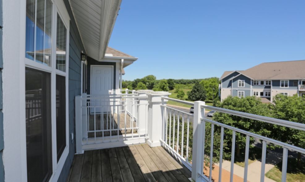 A balcony with a white railing and a view of a house.