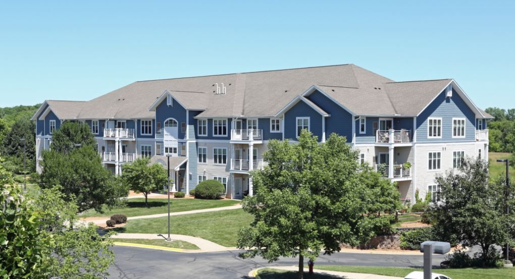 A large blue and white apartment building with trees in front of it
