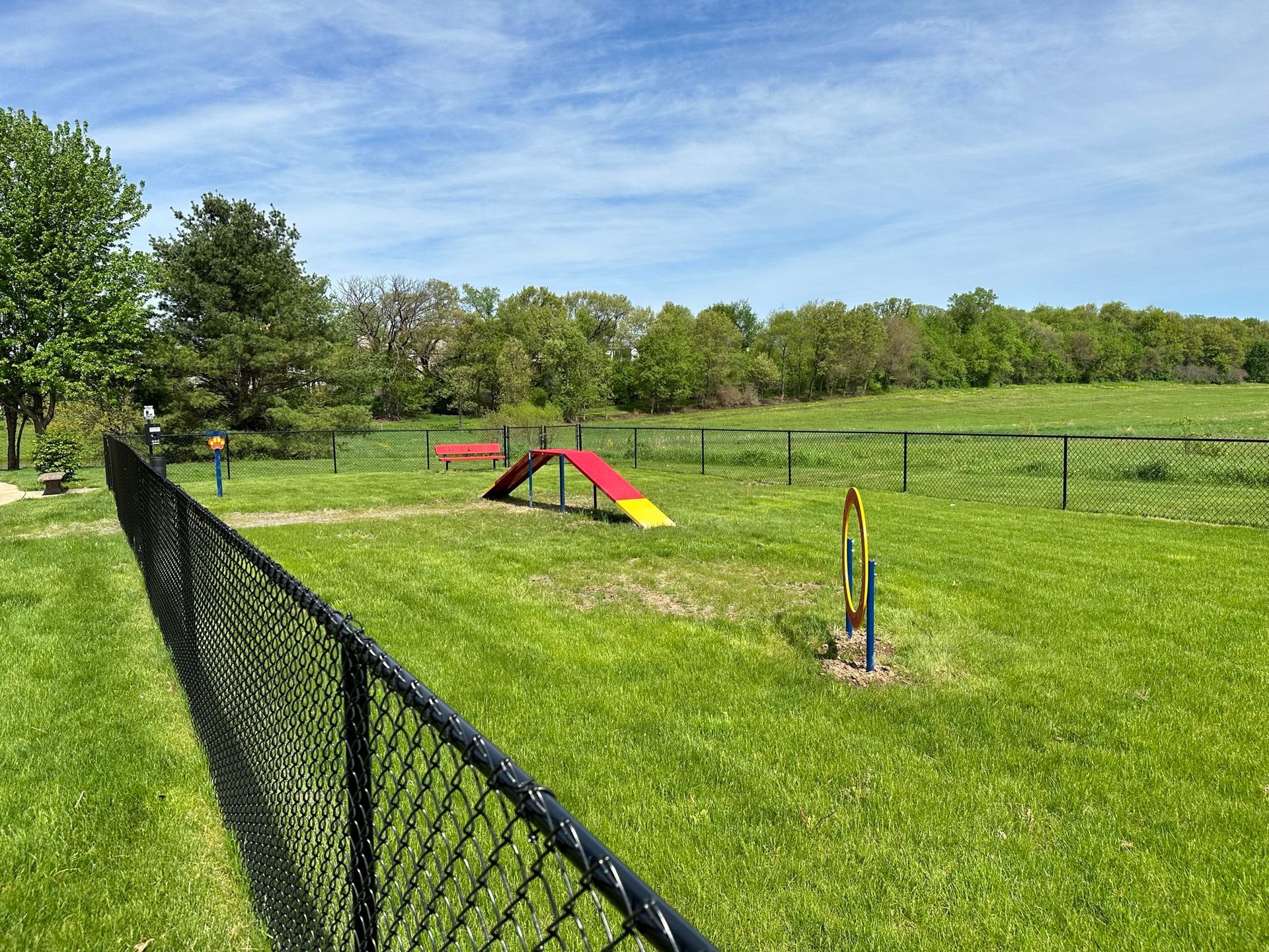 There is a dog park behind a chain link fence.