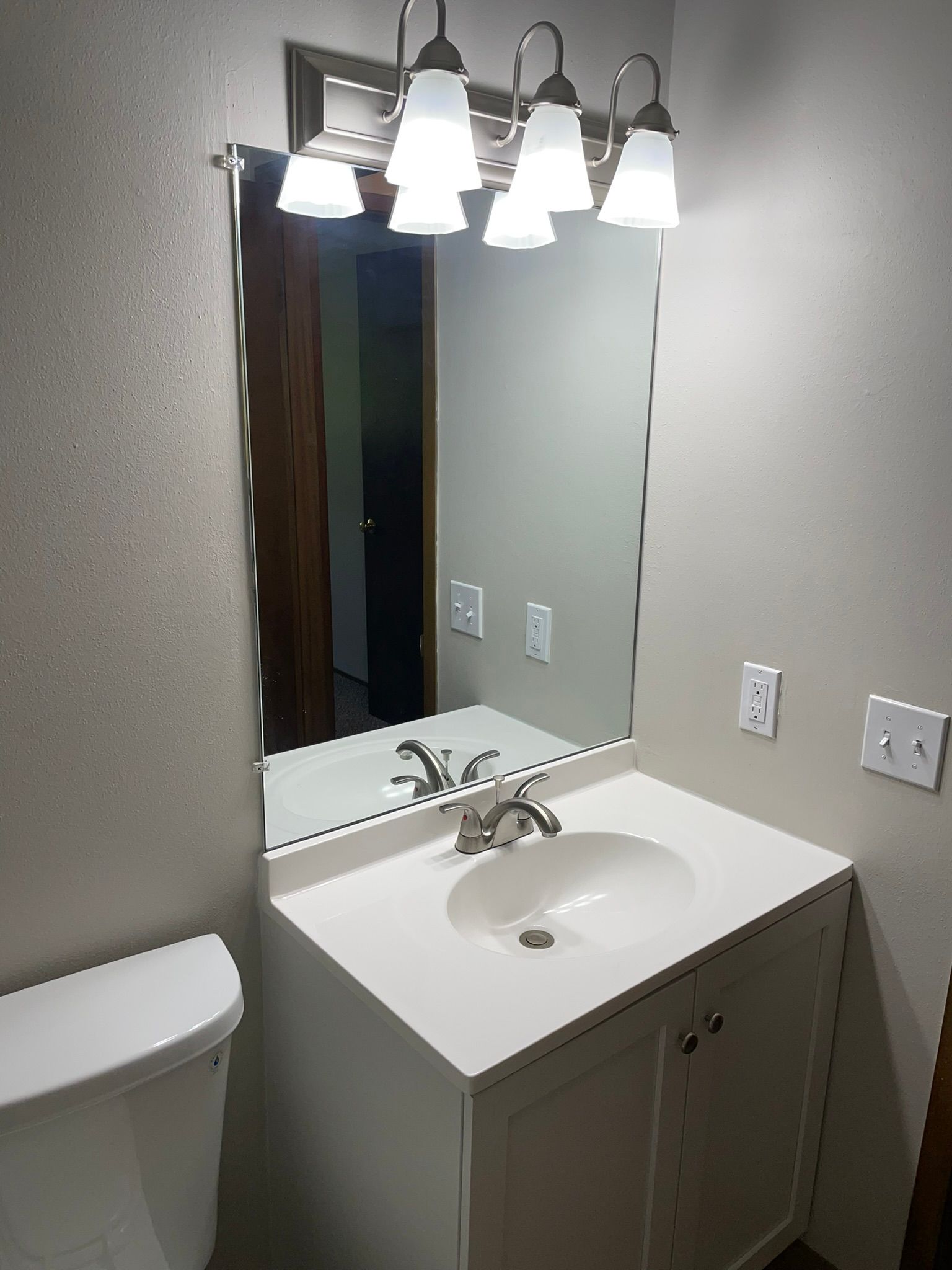 A bathroom with a sink , toilet and mirror.