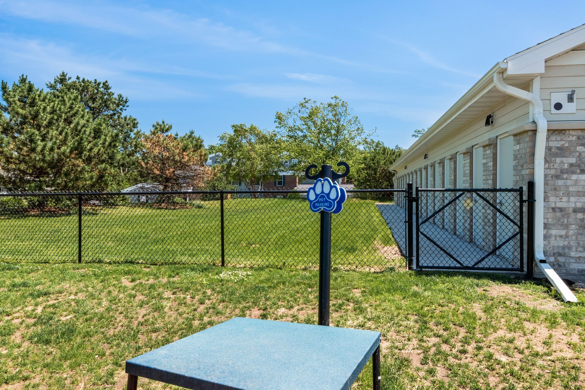 A dog park with a table and a fence in front of a house.