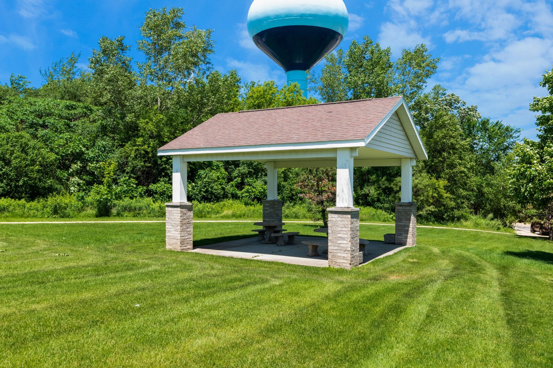 A pavilion in a park with a water tower in the background.