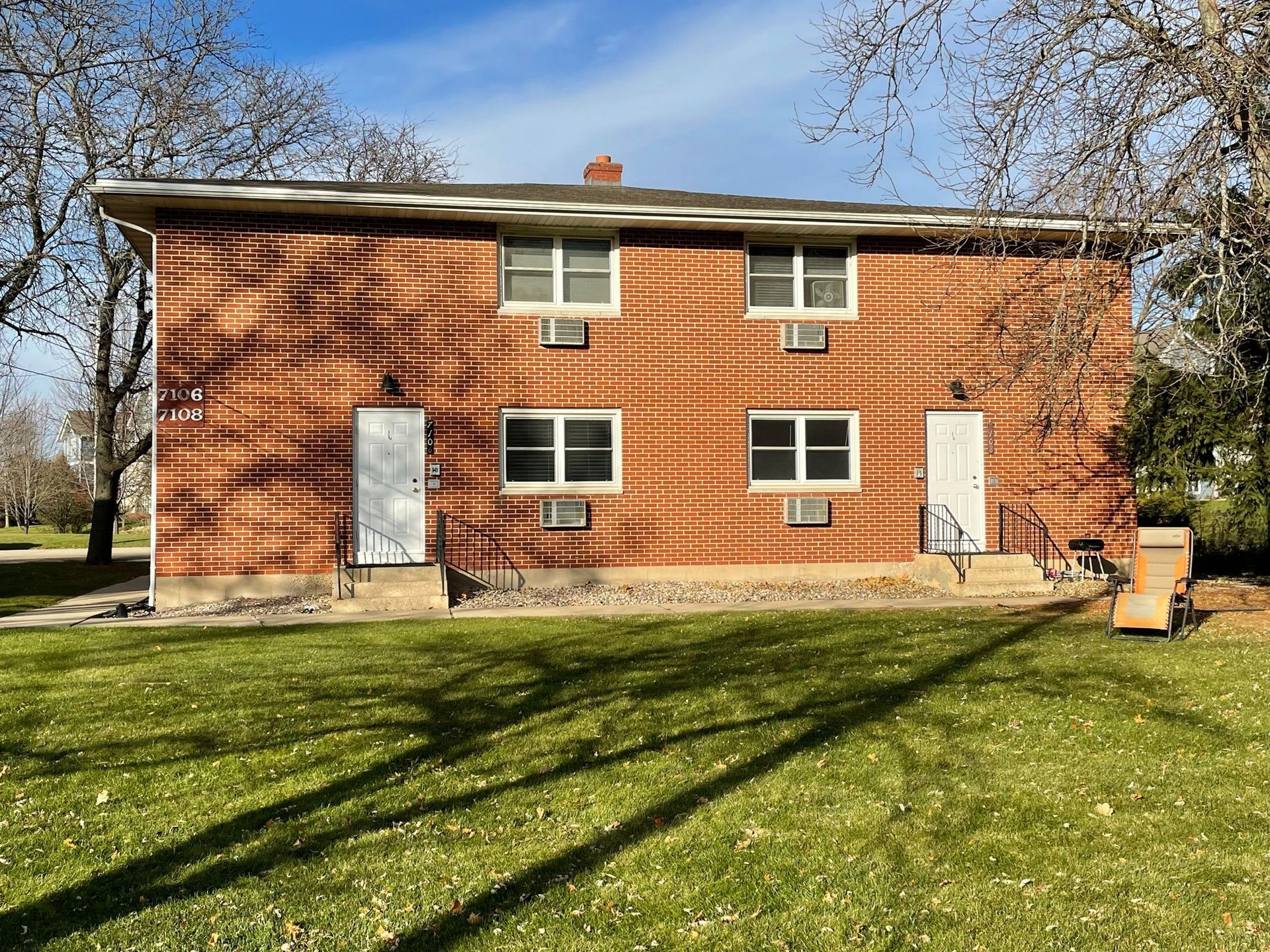 A large brick building with a lot of windows is sitting on top of a lush green field.