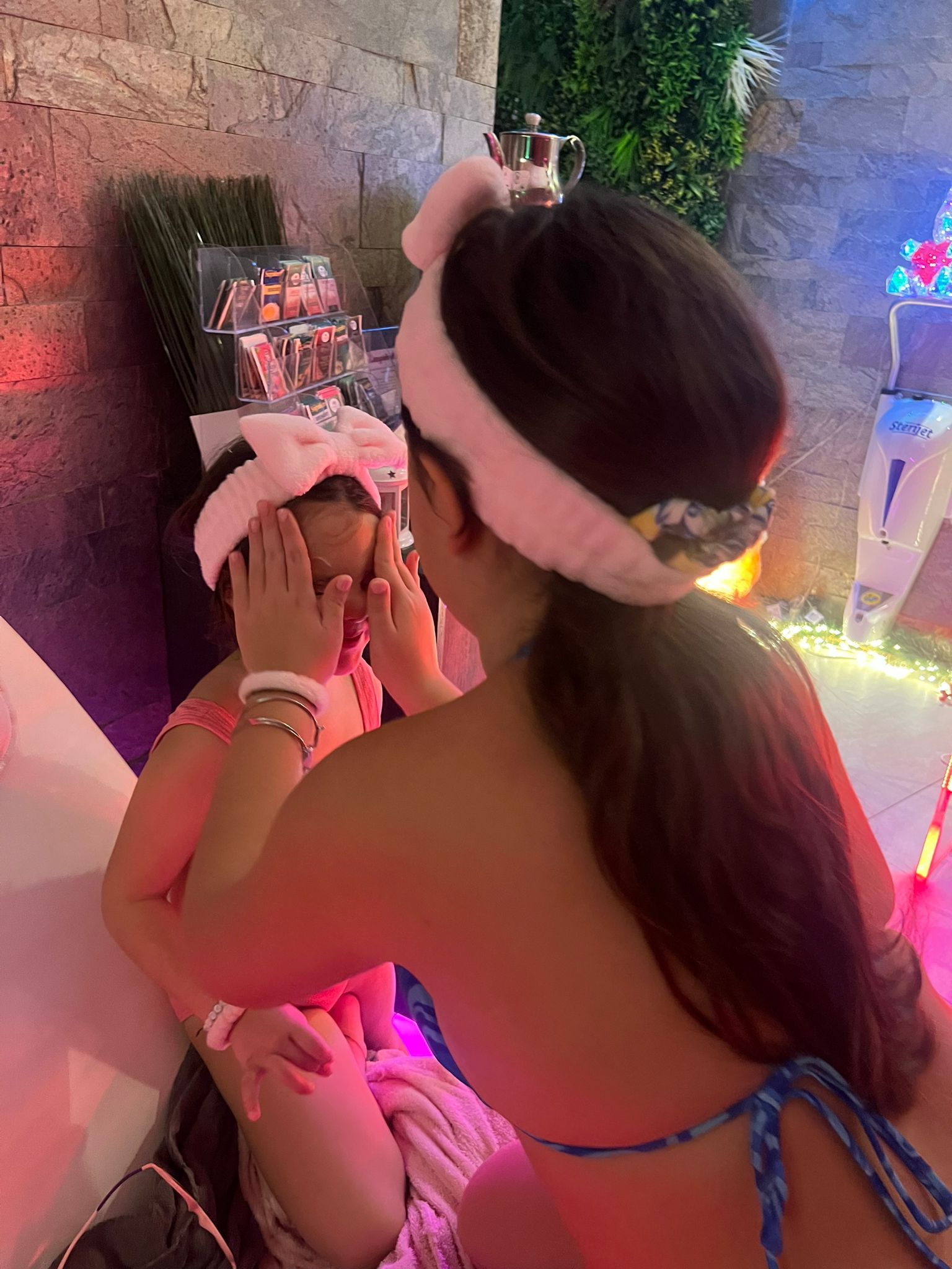 Una donna in bikini sta truccando il viso di un'altra donna.