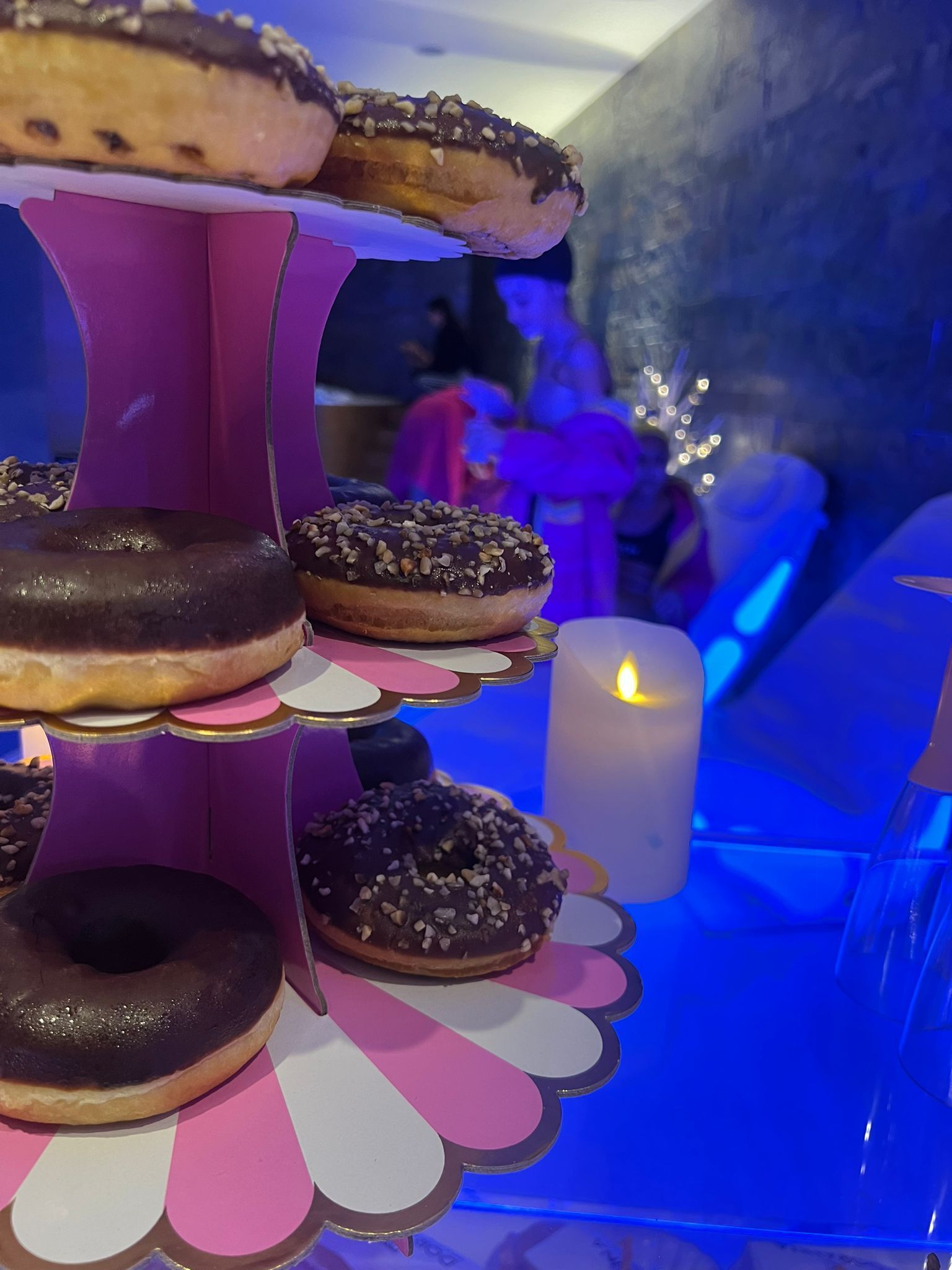 Una candela è appoggiata accanto a una pila di ciambelle su un tavolo.