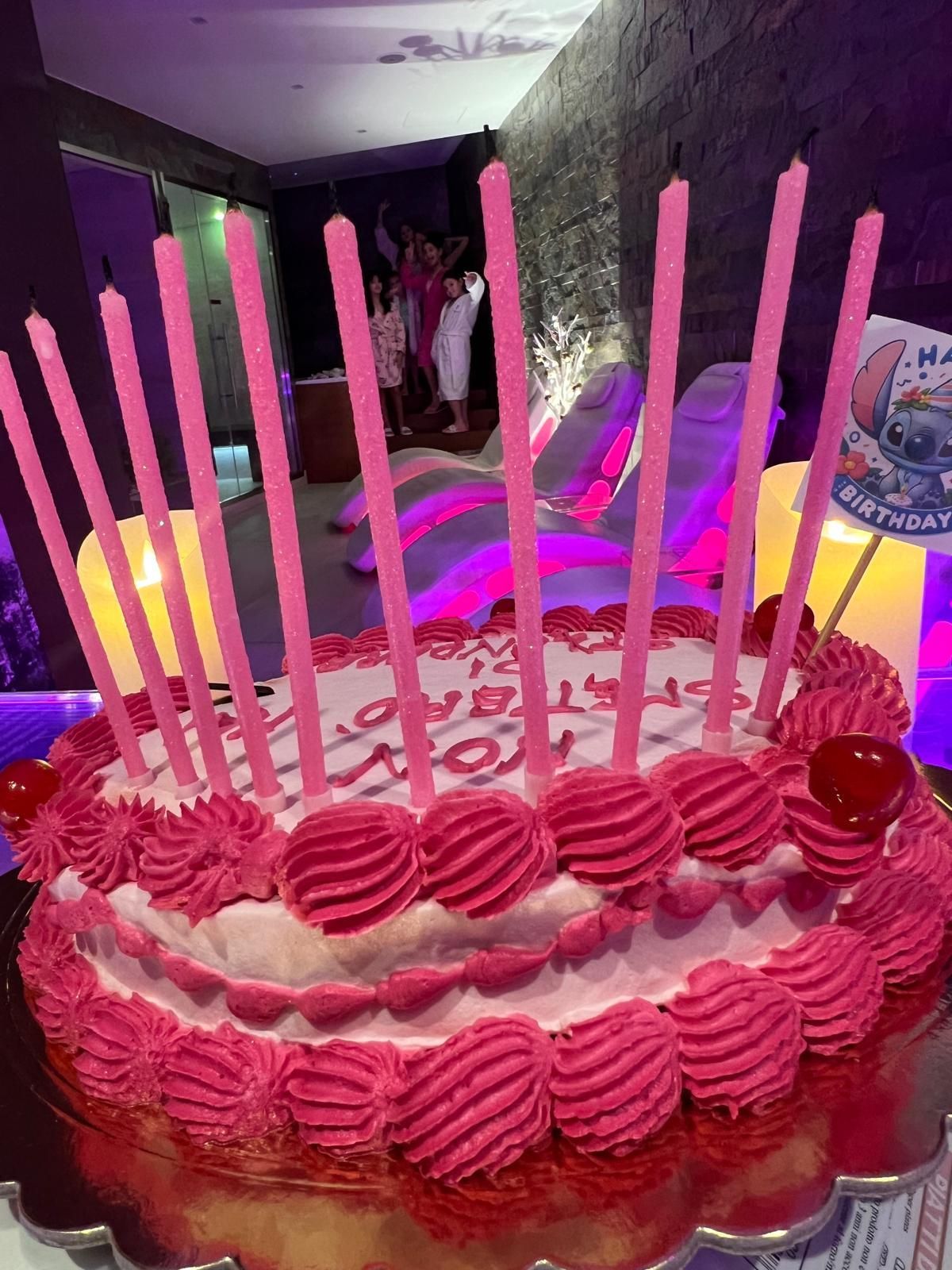 Una torta di compleanno con glassa rosa e candeline sopra