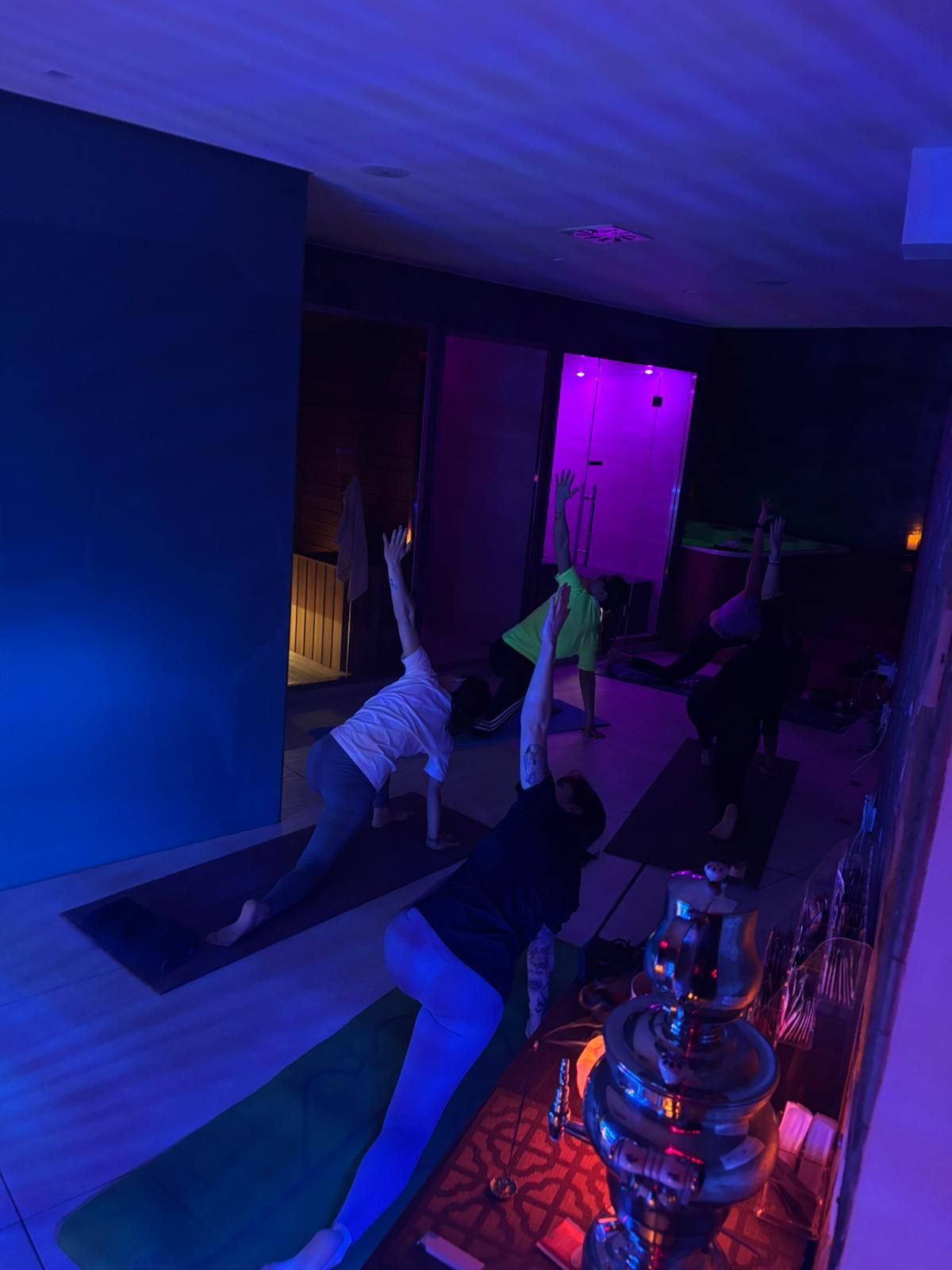 Un gruppo di persone sta facendo yoga in una stanza buia.