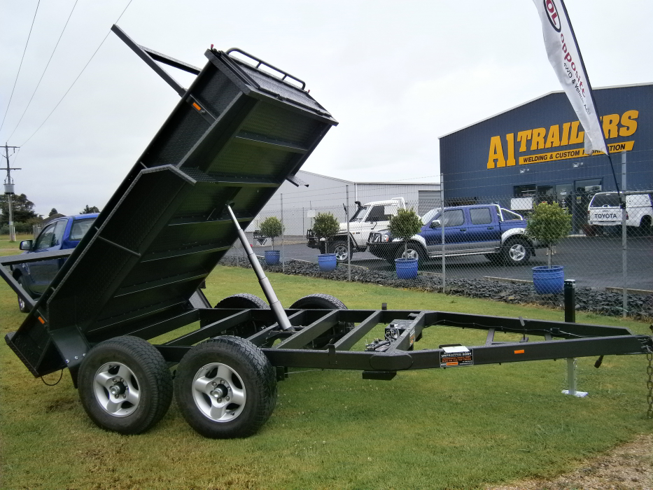A dump trailer is parked in front of a building that says ai trailers