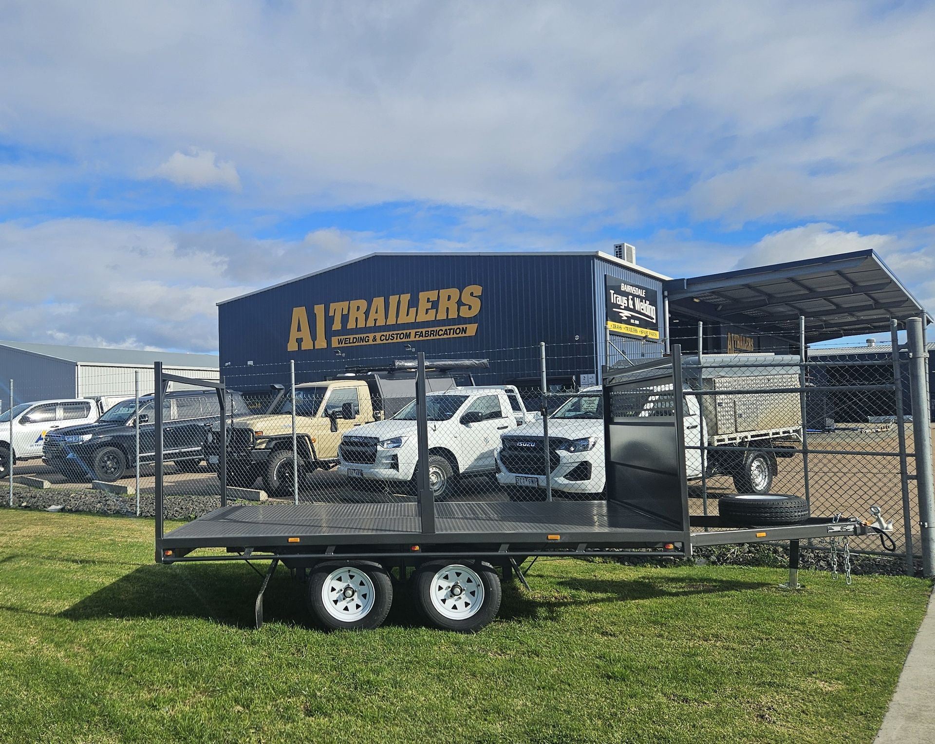A black trailer is parked on the side of the road next to a truck.