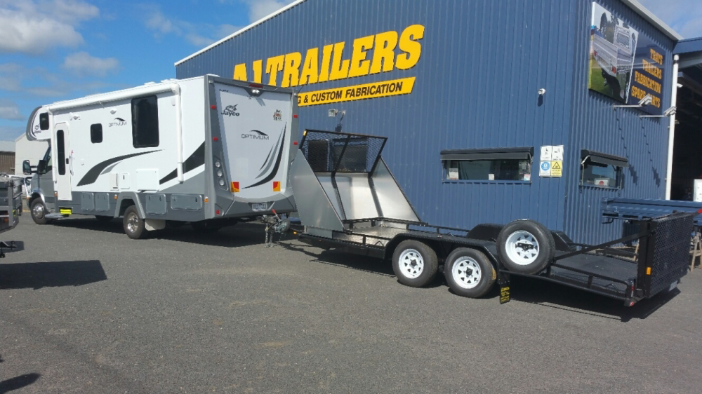 A trailer is being towed by a rv in front of a trailers building.