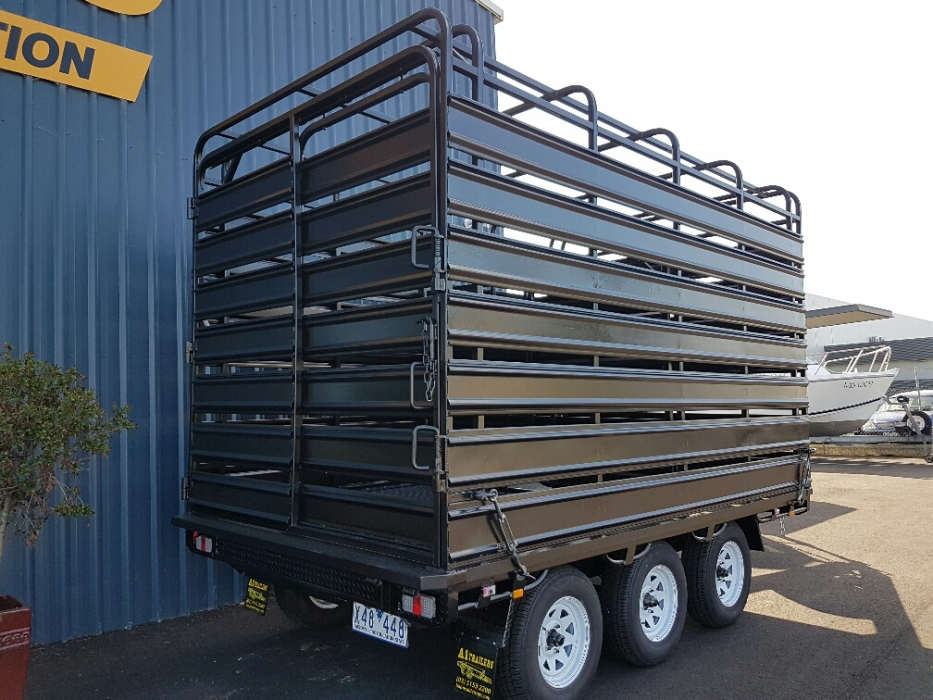 A trailer with a fence on top of it is parked in front of a building.