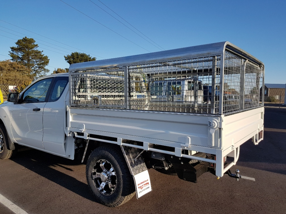 A white truck with a cage on the back is parked in a parking lot.