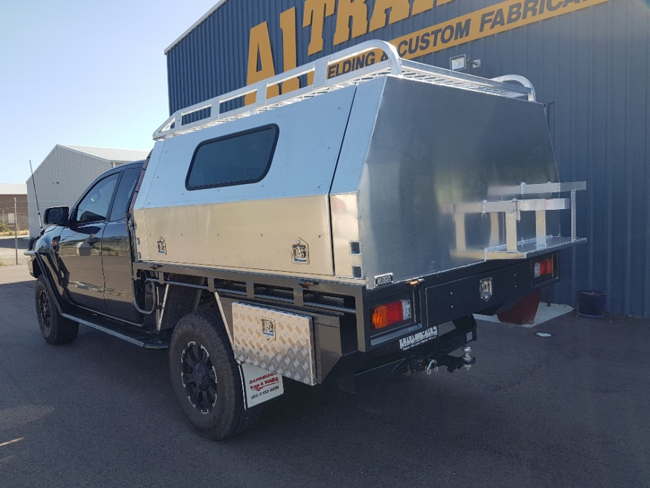 A truck with a canopy on top of it is parked in front of a building.