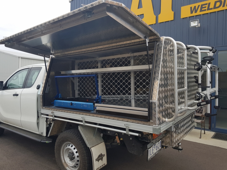 A white truck with the canopy open is parked in front of a building.