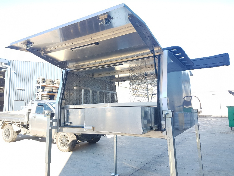 A stainless steel truck canopy is parked in a parking lot.