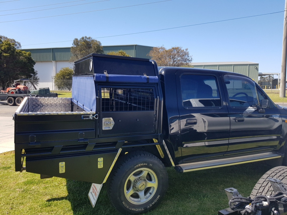 A black truck with a cage in the back is parked on the grass.