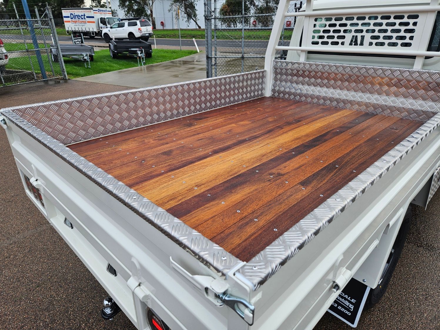 A silver truck with a canopy on top of it is parked on the side of the road.