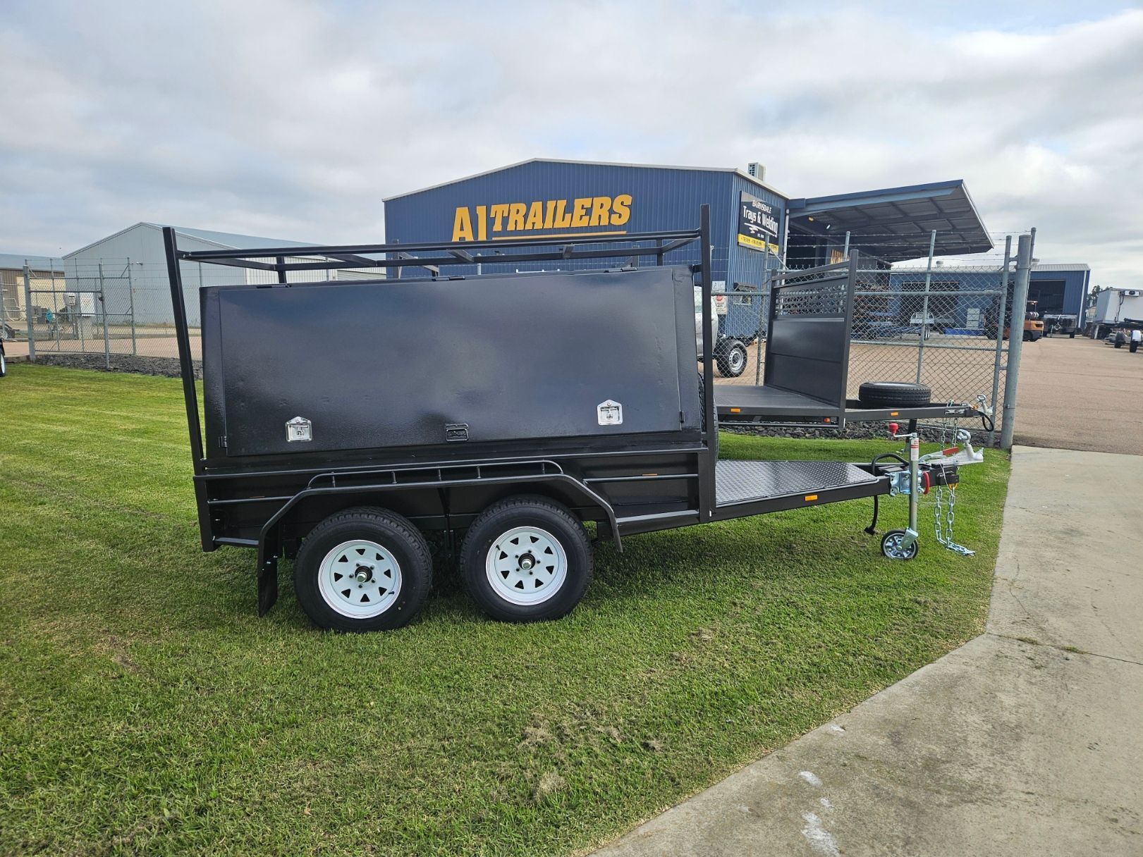A black trailer is parked in front of a building that says a trailers.