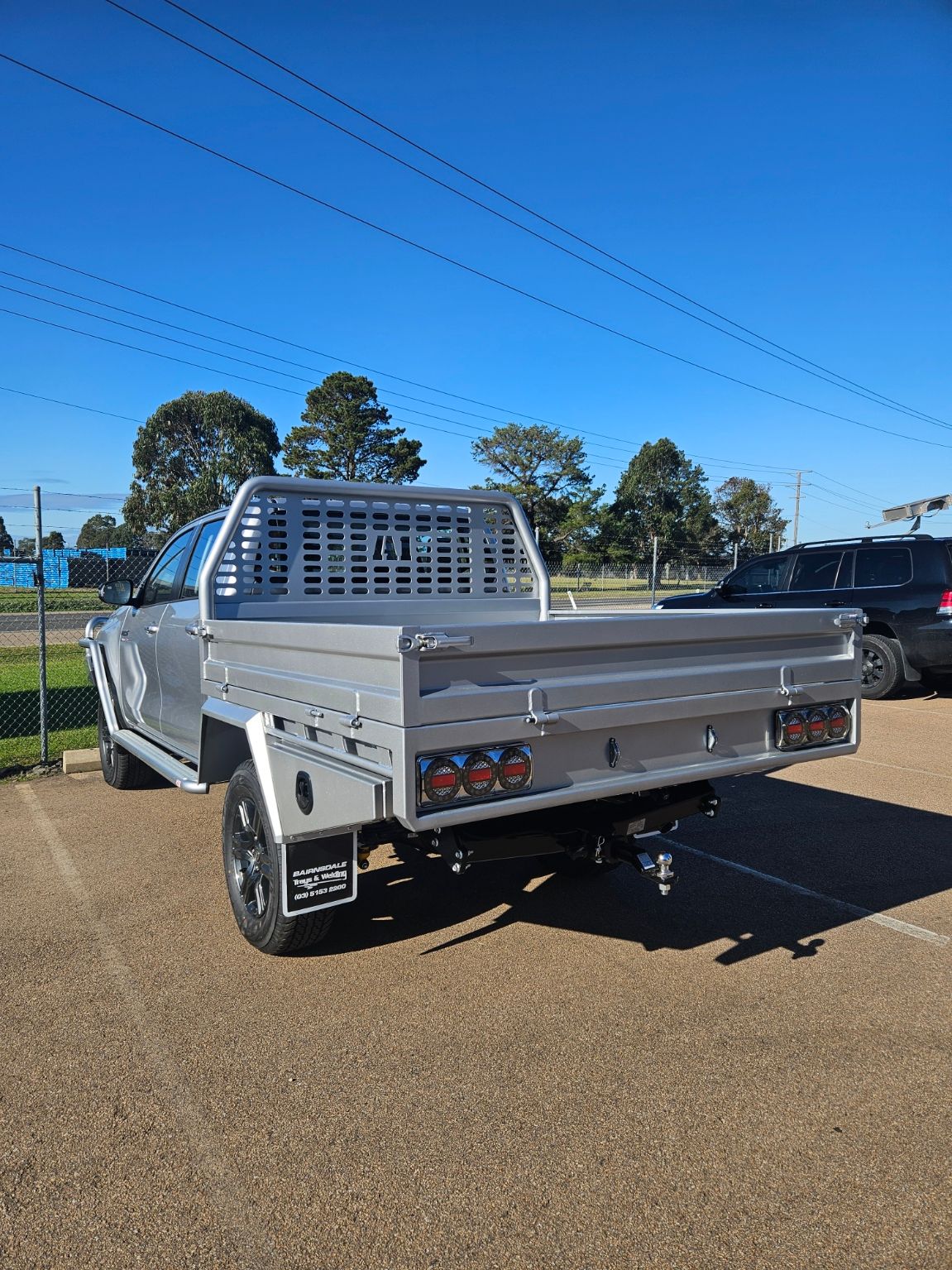 A blue truck with a tray bed is parked in front of a building.