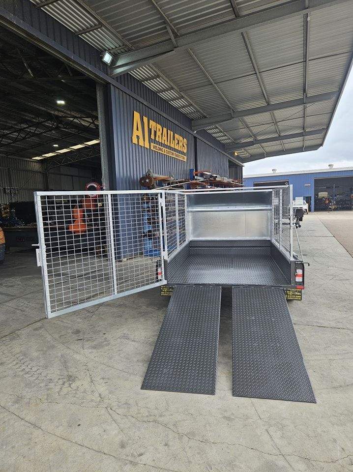 A trailer is parked in front of a building with its doors open.