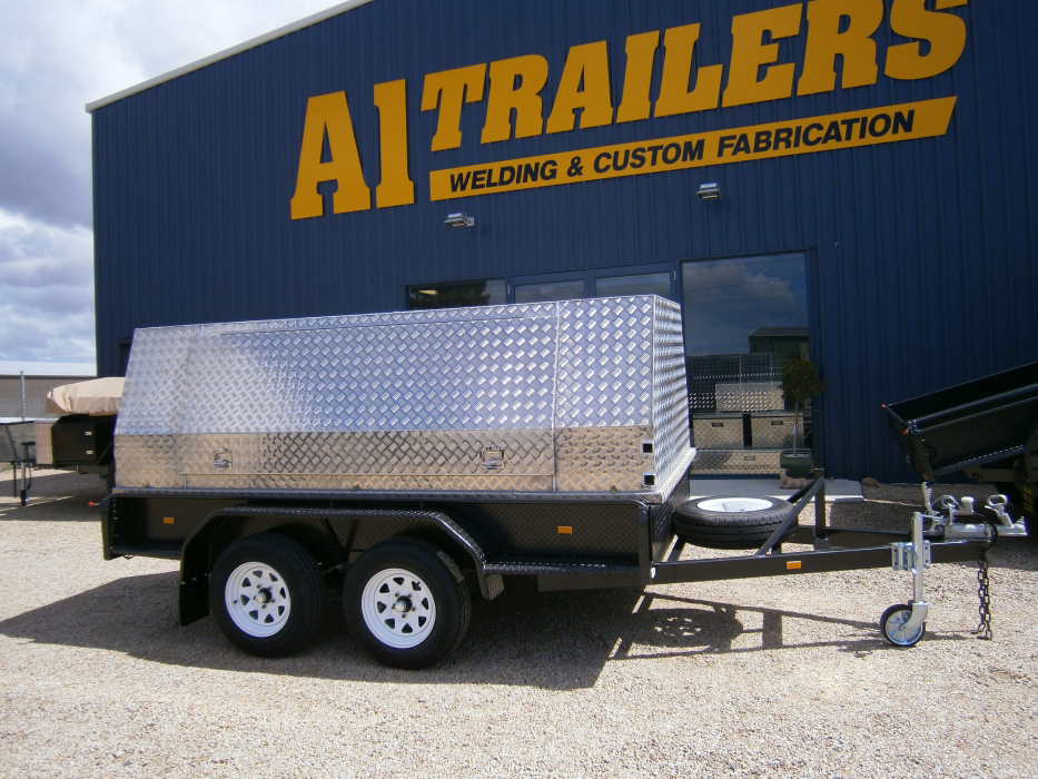 A trailer is parked in front of a building that says ai trailers