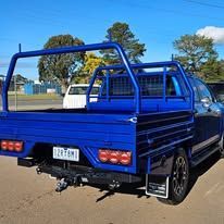 Blue pickup truck with a metal frame, parked outside on a sunny day.