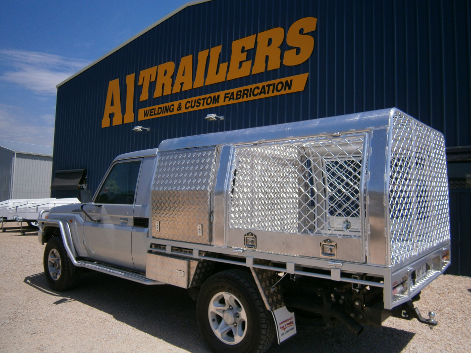 A truck is parked in front of a building that says ai trailers