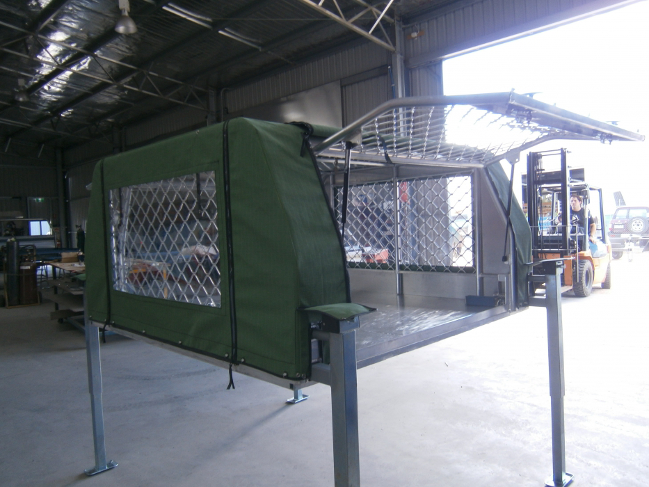 A green canopy is sitting in a warehouse next to a forklift.