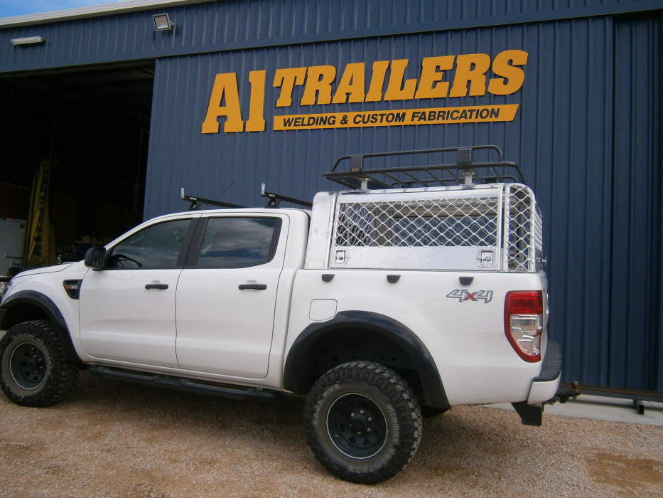 A white truck is parked in front of a building that says ai trailers