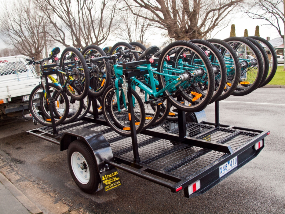 A trailer filled with bicycles is parked on the side of the road.