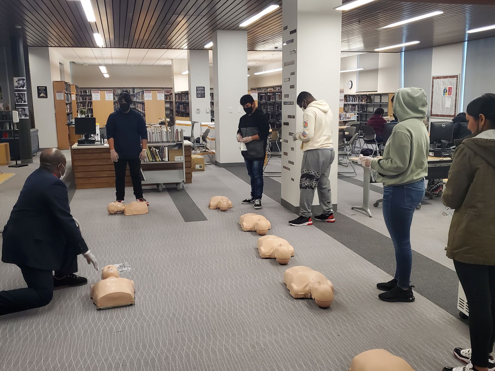 A group of people are practicing first aid in a library.